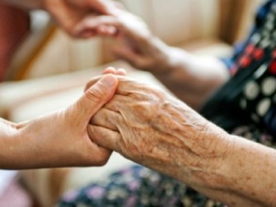A younger persons hands joined with an elderly persons hands