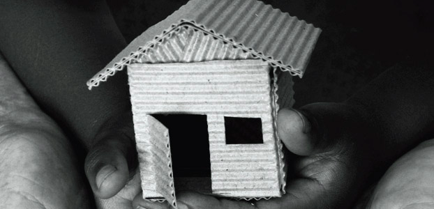 Hands holding a model house made or cardboard