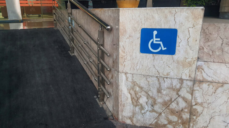An image of a wheelchair ramp with a blue wheelchair sign.