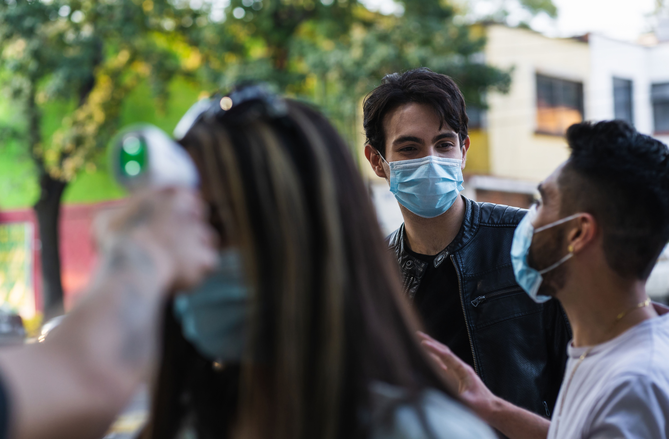 Latin American man hanging out with friends wearing masks during the COVID-10 pandemic.