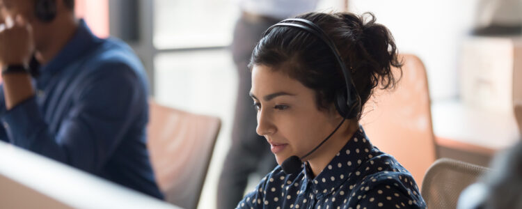 Focused Indian female professional crisis call center agent operator wearing wireless headset work in customer care support service team.