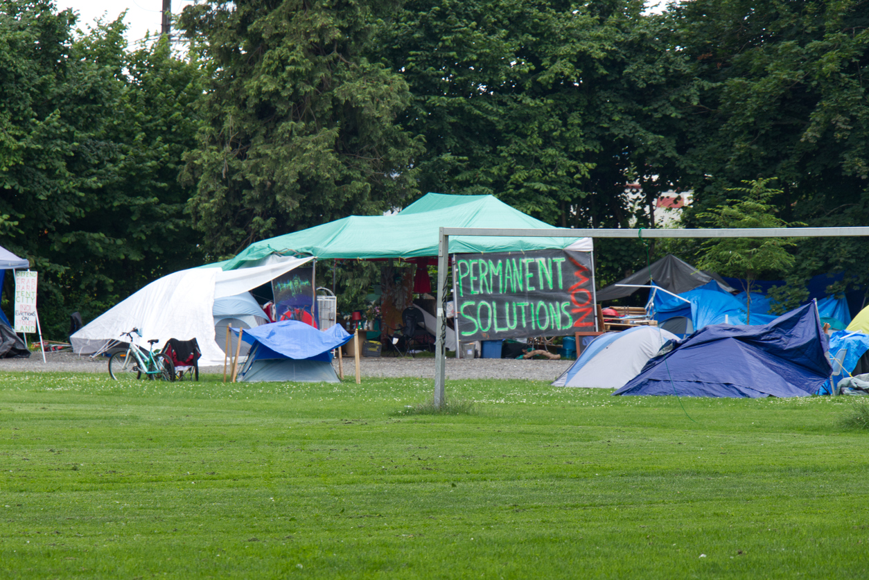 Tents in a park with a sign that says "Permanent solutions"